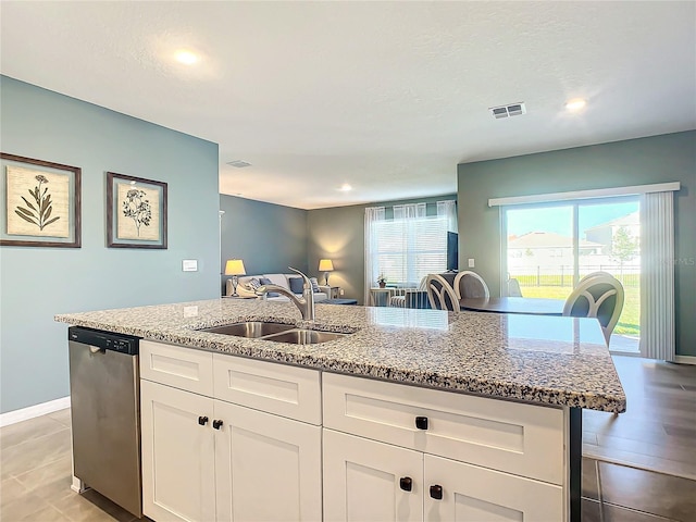 kitchen with light stone countertops, dishwasher, sink, a center island with sink, and white cabinets