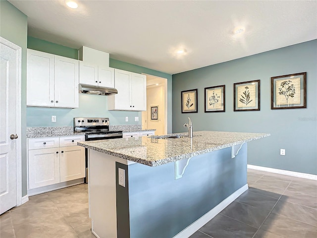 kitchen with light stone counters, stainless steel electric stove, a kitchen island with sink, sink, and white cabinets