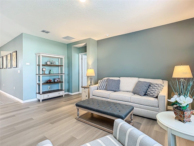 living room with light hardwood / wood-style floors and a textured ceiling