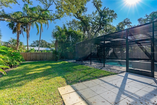 view of yard featuring a fenced in pool, glass enclosure, and a patio