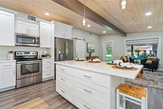 kitchen featuring wooden ceiling, stainless steel appliances, a barn door, beamed ceiling, and a kitchen bar