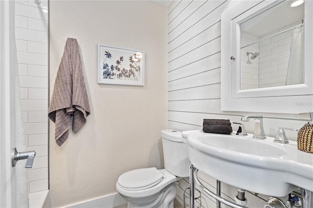 bathroom with a shower with curtain, wood walls, and toilet