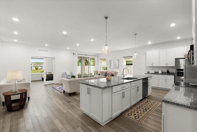 kitchen with a kitchen island with sink, sink, wood-type flooring, white cabinetry, and hanging light fixtures