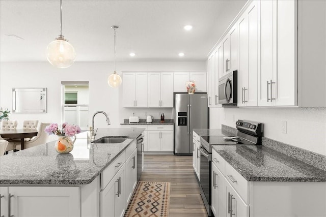 kitchen with white cabinets, decorative light fixtures, sink, and appliances with stainless steel finishes