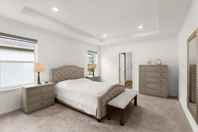 bedroom featuring a tray ceiling and light colored carpet