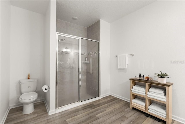 bathroom featuring toilet, a shower with shower door, a textured ceiling, and hardwood / wood-style flooring