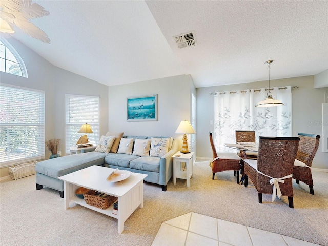 living room with light tile patterned floors, a textured ceiling, light colored carpet, visible vents, and vaulted ceiling