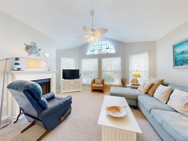 living area featuring ceiling fan, a textured ceiling, light carpet, a fireplace, and vaulted ceiling