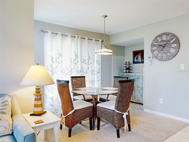 carpeted dining room with a textured ceiling and baseboards