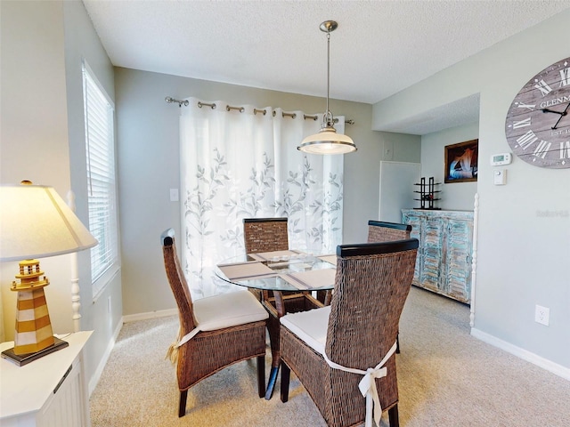 dining space featuring light carpet, a textured ceiling, and baseboards