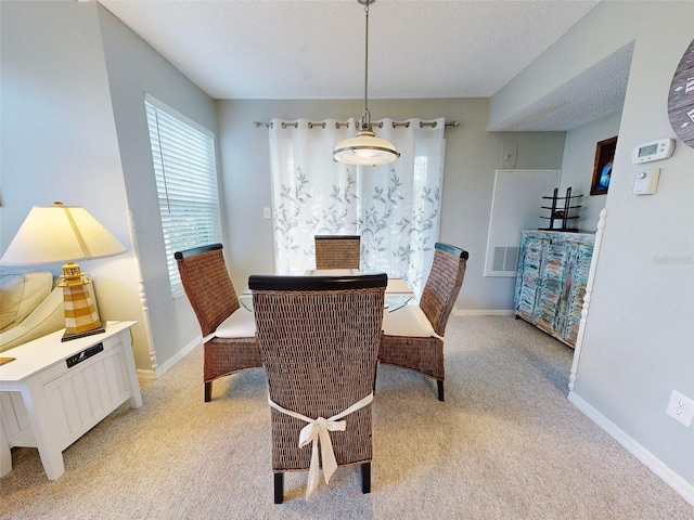 dining space with baseboards, a textured ceiling, visible vents, and light colored carpet