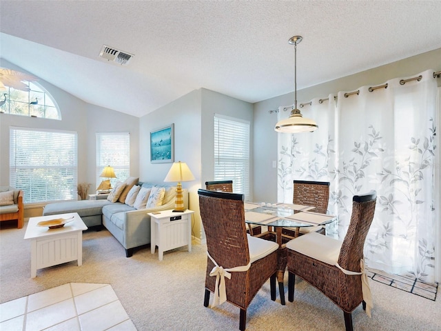 dining room featuring light carpet, visible vents, lofted ceiling, a premium fireplace, and a textured ceiling