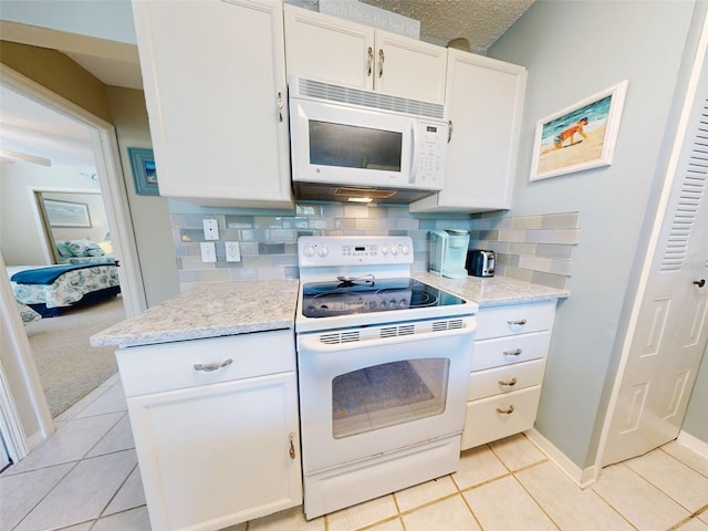 kitchen featuring light stone counters, light tile patterned floors, decorative backsplash, white cabinetry, and white appliances