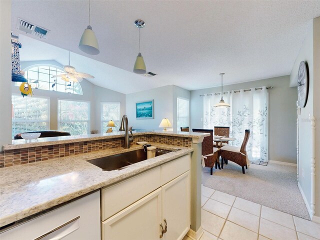 kitchen featuring light colored carpet, a sink, visible vents, plenty of natural light, and pendant lighting