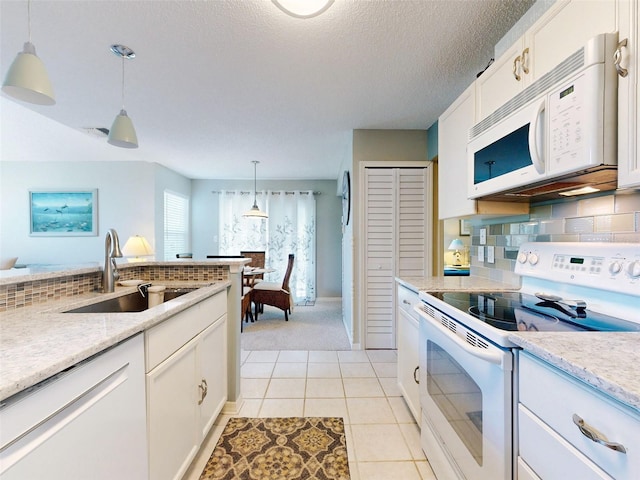 kitchen with pendant lighting, white appliances, white cabinetry, and a sink