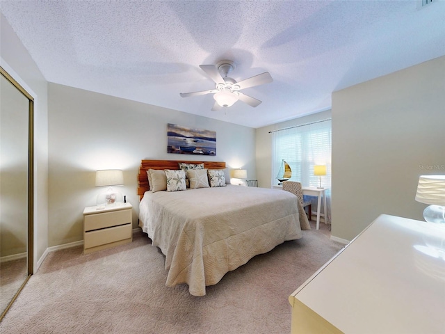 bedroom with light carpet, a closet, a textured ceiling, and a ceiling fan