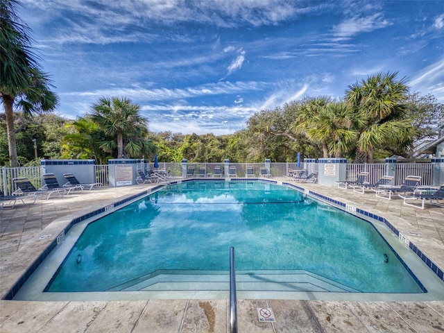 community pool with a patio area and fence