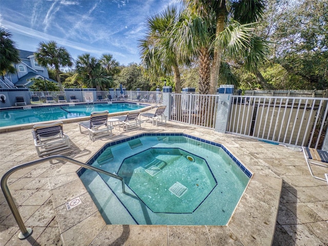 community pool featuring a patio area, fence, and a community hot tub