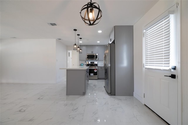 kitchen featuring stainless steel appliances, decorative light fixtures, a notable chandelier, gray cabinets, and a kitchen island