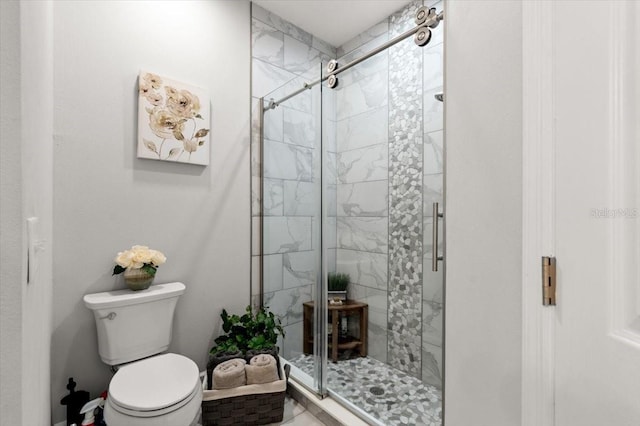 bathroom featuring a shower with shower door and toilet