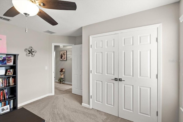 unfurnished bedroom with ceiling fan, light colored carpet, and a closet