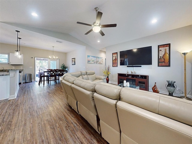 living room featuring ceiling fan with notable chandelier, dark hardwood / wood-style flooring, and vaulted ceiling