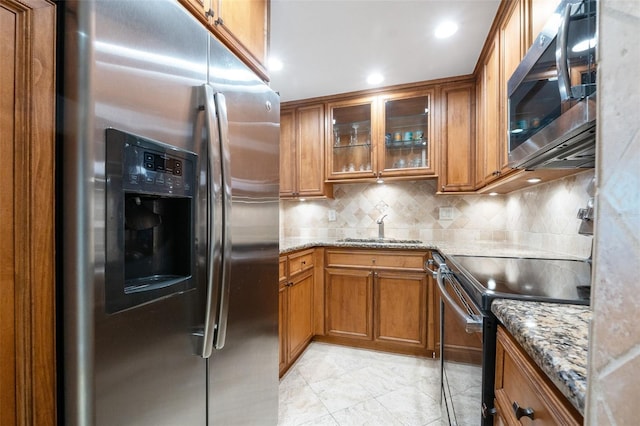 kitchen with sink, decorative backsplash, light stone counters, and stainless steel appliances