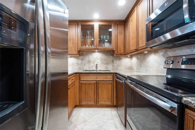 kitchen with decorative backsplash, light stone countertops, sink, and appliances with stainless steel finishes