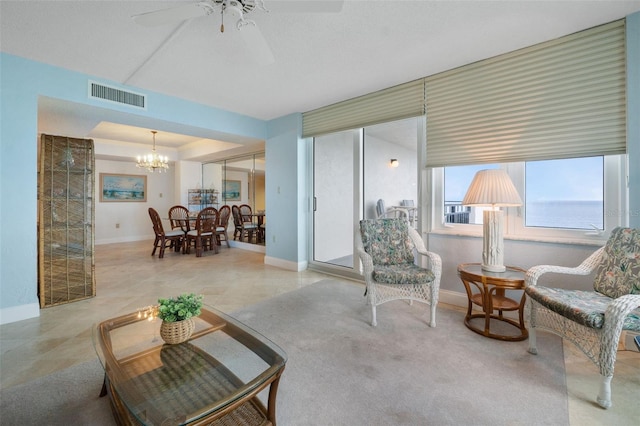 carpeted living room featuring ceiling fan with notable chandelier