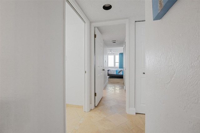 hallway with light tile patterned flooring and a textured ceiling