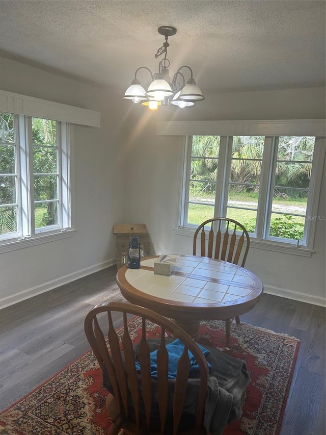 dining space with an inviting chandelier, a textured ceiling, and dark hardwood / wood-style flooring