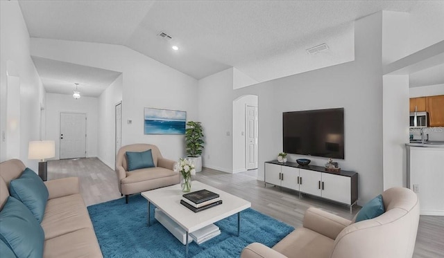 living room featuring light hardwood / wood-style floors and high vaulted ceiling