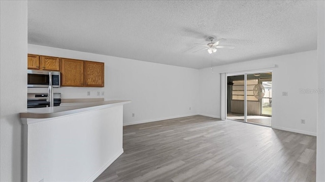 kitchen featuring range, light wood-type flooring, a textured ceiling, and ceiling fan