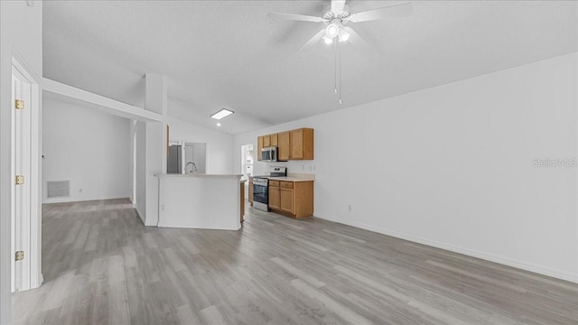 kitchen with ceiling fan, light wood-type flooring, appliances with stainless steel finishes, and vaulted ceiling