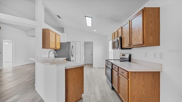 kitchen featuring kitchen peninsula, light hardwood / wood-style floors, a textured ceiling, lofted ceiling, and appliances with stainless steel finishes