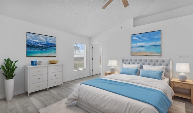 bedroom featuring ceiling fan, light hardwood / wood-style floors, lofted ceiling, and a textured ceiling