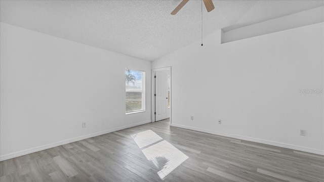 spare room featuring a textured ceiling, light hardwood / wood-style flooring, ceiling fan, and vaulted ceiling