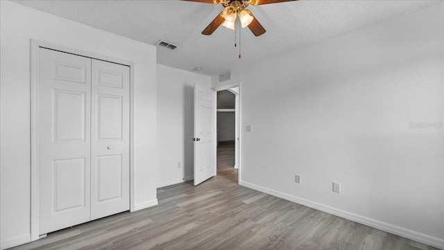 unfurnished bedroom with ceiling fan, light hardwood / wood-style floors, a textured ceiling, and a closet