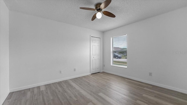 unfurnished room featuring ceiling fan, light hardwood / wood-style floors, and a textured ceiling