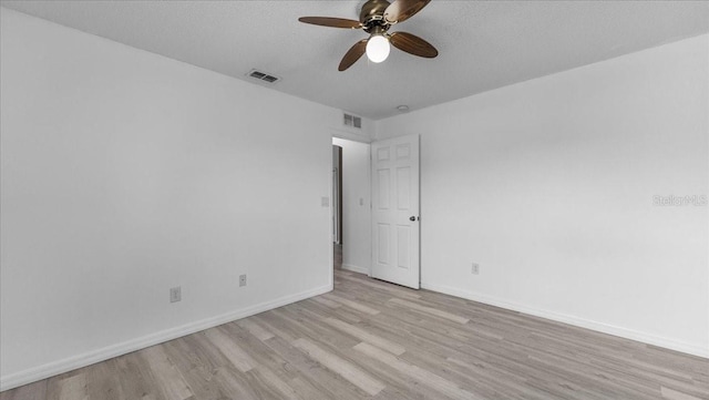 spare room featuring light wood-type flooring, a textured ceiling, and ceiling fan