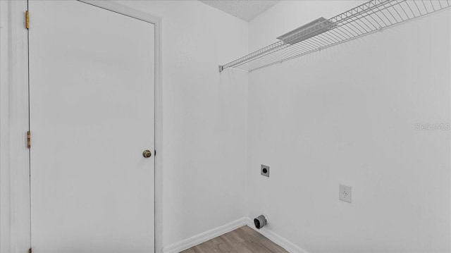 washroom with hookup for an electric dryer, light wood-type flooring, and a textured ceiling