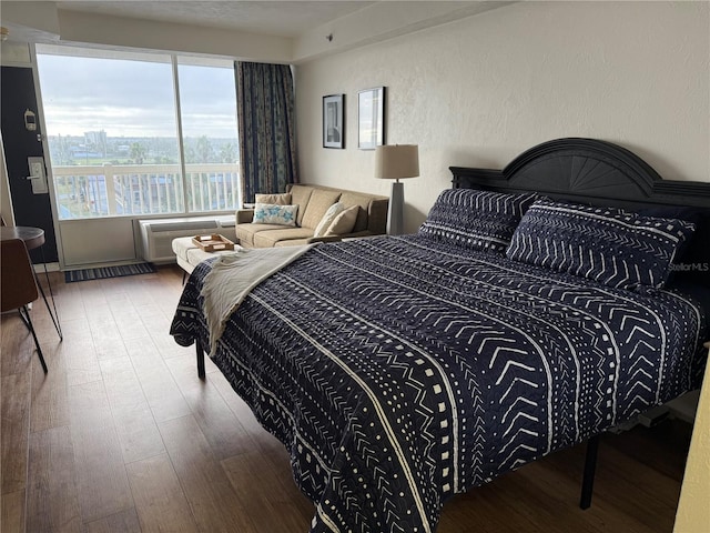 bedroom with an AC wall unit and wood-type flooring