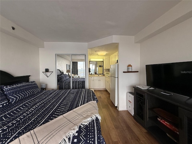 bedroom with dark hardwood / wood-style floors, a closet, ensuite bath, and fridge