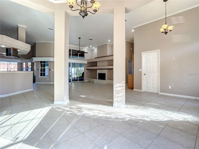 tiled empty room featuring a fireplace, a high ceiling, and ceiling fan with notable chandelier