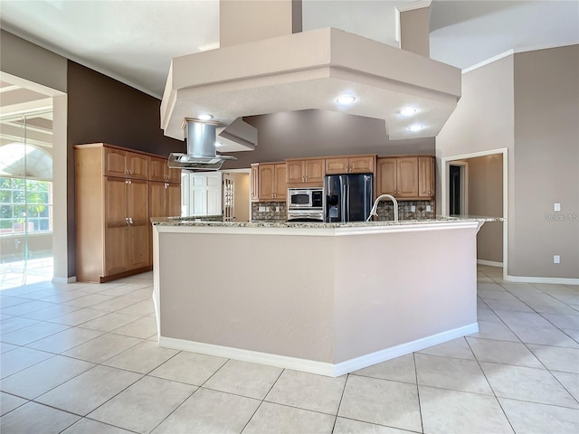 kitchen with stainless steel microwave, tasteful backsplash, refrigerator with ice dispenser, island exhaust hood, and a center island with sink