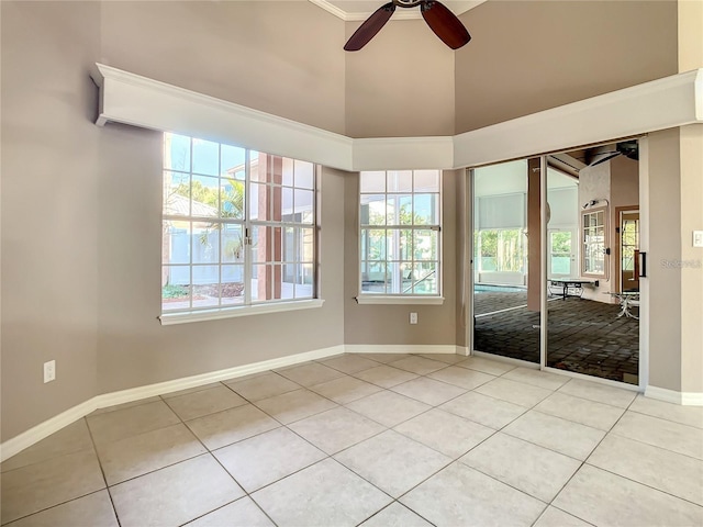 spare room with ceiling fan, light tile patterned flooring, a towering ceiling, and a wealth of natural light