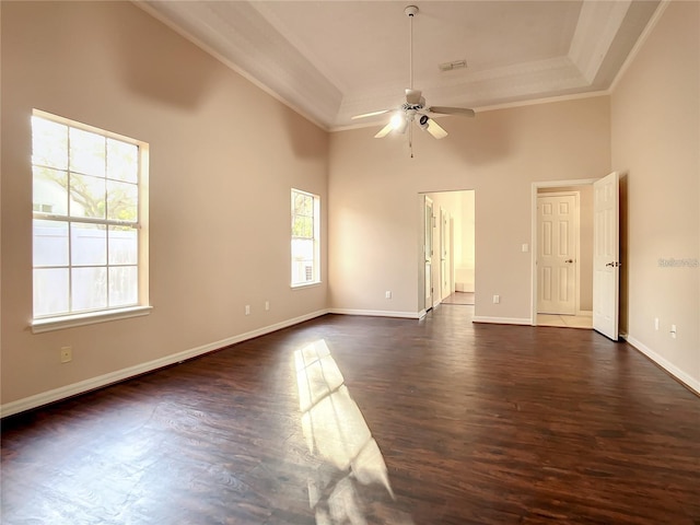 empty room with ceiling fan, a raised ceiling, a towering ceiling, and crown molding