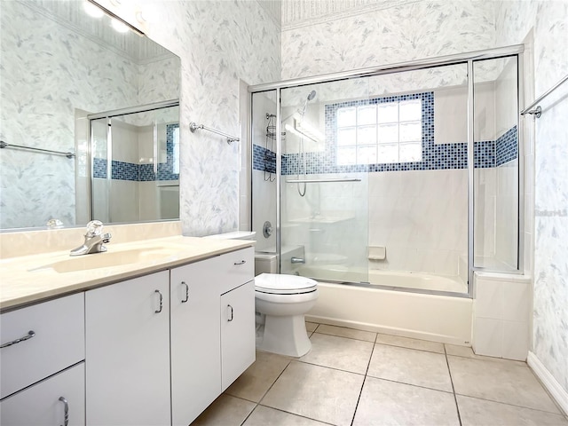 full bathroom with tile patterned floors, vanity, bath / shower combo with glass door, and toilet