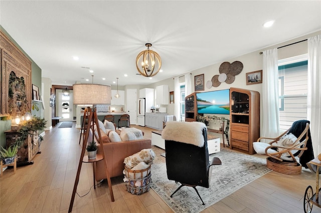 living room with light hardwood / wood-style floors and a notable chandelier