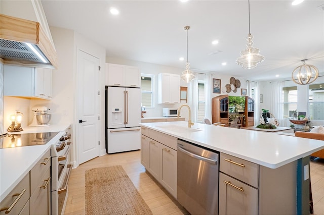 kitchen with white cabinetry, a large island, sink, decorative light fixtures, and white appliances